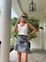 Minifalda de denim celeste con efecto lavado, corte acampanado y ruedo desflecado.