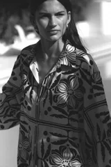 Camisa de corte holgado con estampado floral en blanco y negro, cuello clásico, mangas largas y cierre frontal con botones.