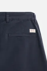 Pantalón chino azul marino, corte skinny fit, confeccionado en tejido de algodón con elasticidad. Cuenta con bolsillos frontales y traseros de vivo. Cierre frontal con cremallera y botón.