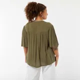 Blusa color verde oliva con bordados blancos en el frente y en el cuello, mangas 3/4 abullonadas y cierre frontal con botones.