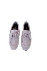 Mocasín gris de cuero gamuzado con lazo frontal y detalle de pasacintas laterales. Suela flexible antideslizante.