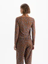 Top de punto color rojo con estampado de labios en azul y fucsia. Presenta escote en V profundo con jareta ajustable para anudar, mangas largas y calce al cuerpo.