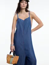 Mono largo de denim azul oscuro, con breteles finos regulables, escote recto, bolsillos traseros y corte amplio de pierna recta.