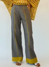 Pantalón gris de lino con corte palazzo y detalle de costuras amarillas en los laterales y en el ruedo.