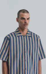 Camisa de manga corta con cuello cubano y estampado a rayas verticales en tonos azul, amarillo y rojo.