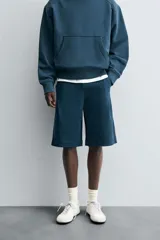 Bermuda azul petróleo de corte relaxed fit, confeccionada en algodón. Tiene cintura elástica ajustable con cordón, bolsillos laterales y un bolsillo trasero.