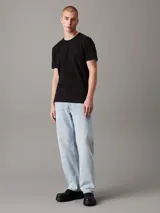 Remera negra de algodón con cuello redondo y mangas cortas. Cinta con logo de Calvin Klein Jeans en espiguilla en los laterales.