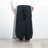 Pantalón de jean negro de corte ancho, con detalles de flecos diagonales en la parte delantera.