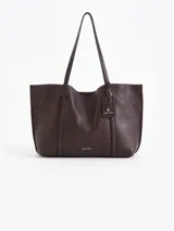 Cartera shopper de cuero vacuno flor color marrón oscuro, con grabados de cerezas distribuidos en la superficie. Tiene acceso mediante imán, manijas de cuero y un bolsillo interior desmontable con cierre metálico. Incluye un tag decorativo con un mini aplique de cereza.