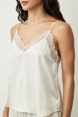 Blusa color crudo con lunares dorados, breteles finos y escote en V con detalle de encaje.