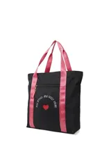 Bolso tipo tote bag negro con estampa de texto y corazón rojo. Tiene asas de color rosa con texto en blanco.