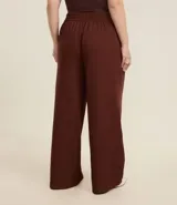 Pantalón de vestir marrón de corte wide leg, confeccionado en viscosa y poliéster. Presenta cintura con elástico en la espalda y cierre delantero con ganchillo, botón y cremallera.