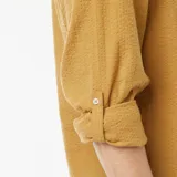 Camisa color mostaza de manga larga con cuello mao y cierre parcial con botones.