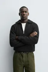 Jersey de punto perlado negro, de corte relaxed fit, con cuello perkins y cierre frontal de cremallera.