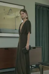 Vestido largo de fiesta color verde oscuro con brillos dorados, escote en V profundo, mangas cortas con volados y cintura elastizada.