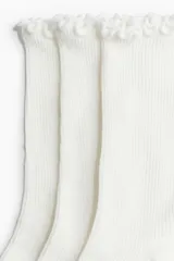 Pack de cinco pares de medias blancas de algodón acanalado, con largo a la pantorrilla y detalle de volados en el borde superior.