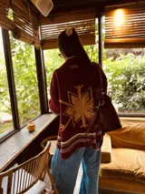 Cardigan tejido artesanalmente en lana color crudo, con diseño de copo de nieve en la espalda y bordados a mano.