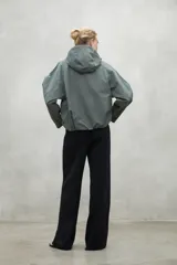 Campera color crema de corte oversize con capucha ajustable, cierre frontal con botones a presión y bolsillos laterales con solapa. Fabricada con poliamida reciclada, impermeable y transpirable.