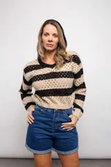 Buzo de punto calado a rayas horizontales en tonos beige y negro, con capucha y corte holgado.