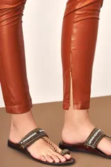 Pantalón legging de cuero color marrón con cierre en los bolsillos.