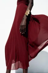 Vestido midi color borgoña con escote en V, tirantes anchos con detalle de nudo y falda plisada. Cierre trasero con cremallera oculta.