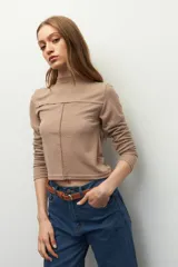 Polera negra de manga larga con cuello alto y costuras a la vista en el frente.