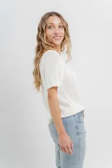 Remera tejida de manga corta, color gris claro, con escote en V y calce relajado. Presenta terminaciones acanaladas en mangas y ruedo.