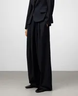Pantalón sastre de pierna ancha en color azul marino, con pliegues delanteros y cierre cruzado. Incluye bolsillos laterales y bolsillos de vivo en la parte posterior, confeccionado en una mezcla de poliéster, lana merino y viscosa.