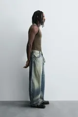 Pantalón de jean celeste con efecto lavado, corte holgado desde la cadera que se estrecha ligeramente en el bajo, tiro medio, cinco bolsillos y cierre frontal con cremallera y botón.