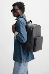 Mochila negra con textura grabada, compartimento principal con cierre de cremallera, compartimento acolchado interior para dispositivos electrónicos de hasta 13 pulgadas, bolsillo frontal con cierre de cremallera, dos bolsillos laterales planos, asa de mano y dos asas de hombro ajustables.