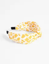 Vincha rígida de tela con nudo, en color blanco y estampado de manchas de color amarillo.