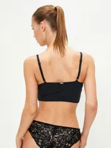 Conjunto de ropa interior negro, compuesto por un bralette de encaje con breteles finos y una bombacha tipo colaless de encaje.
