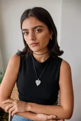 Collar con tiento encerado negro y dije dorado con forma de corazón texturizado.