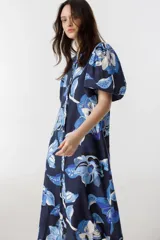 Vestido midi de lino azul marino con estampado floral en tonos celeste y blanco, cuello mao, mangas abullonadas hasta el codo y cierre frontal con botones de nácar.