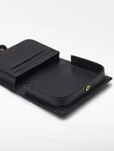 Monedero negro de piel de cordero con estructura rígida, cierre de broche, tarjetero interior, pespunte decorativo a contraste y logo grabado.