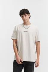 Remera color crema de manga corta con estampado de águilas y texto distorsionado en la espalda. Corte regular.