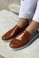 Slippers de cuero celeste con elásticos laterales y suela de goma blanca.