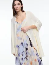 Chal color crema tejido en hilado liviano con brillo sutil y pequeñas lentejuelas al tono. Diseño envolvente y fluido.