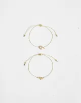 Set de dos pulseras flexibles doradas con dije de corazón y arandela de metal.