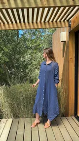 Vestido camisero amplio y largo de lino color azul, con botones de nácar, cuello camisero y bolsillos laterales.