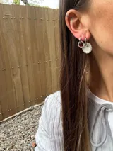Aros de plata con forma de argolla, uno con dije circular con strass plateado y otro con dije circular con strass color borgoña. Se venden por unidad.