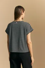 Remera de manga corta con cuello redondo, confeccionada en tejido acanalado a rayas horizontales blancas y negras.