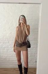 Vestido corto color beige, con escote halter y espalda descubierta. Ajustado al cuerpo y confeccionado en microtul.