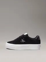 Zapatillas de ante negras con plataforma blanca y logo CK en el lateral.
