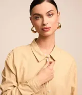Camisa color beige de viscolino con cuello camisero, manga larga, botonadura frontal y corte holgado.