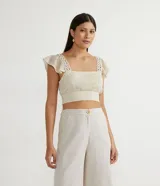 Blusa musculosa cropped color crudo, de algodón texturizado, con escote cuadrado, tirantes anchos con volantes y lastex en el dobladillo.