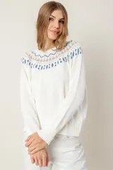 Sweater de punto color crema con diseño geométrico en azul y beige en la parte superior.