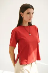 Remera blanca de algodón de corte recto, con cuello redondo y mangas cortas. Presenta detalle de aberturas laterales con ojales metálicos.