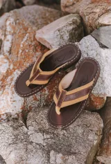 Sandalias tipo ojotas de cuero color marrón claro con tiras de cuero marrón oscuro.