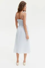 Vestido midi celeste con textura a rayas, cuerpo entallado fruncido, escote redondo y breteles spaghetti. Costura fruncida en la cintura y pollera con leve vuelo.